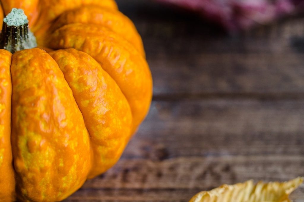 Small pumpkin with autumn leaves on a wood table