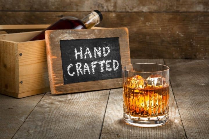 craft-alcohol-only@2x Glass of whiskey in front of sign reading Hand Crafted