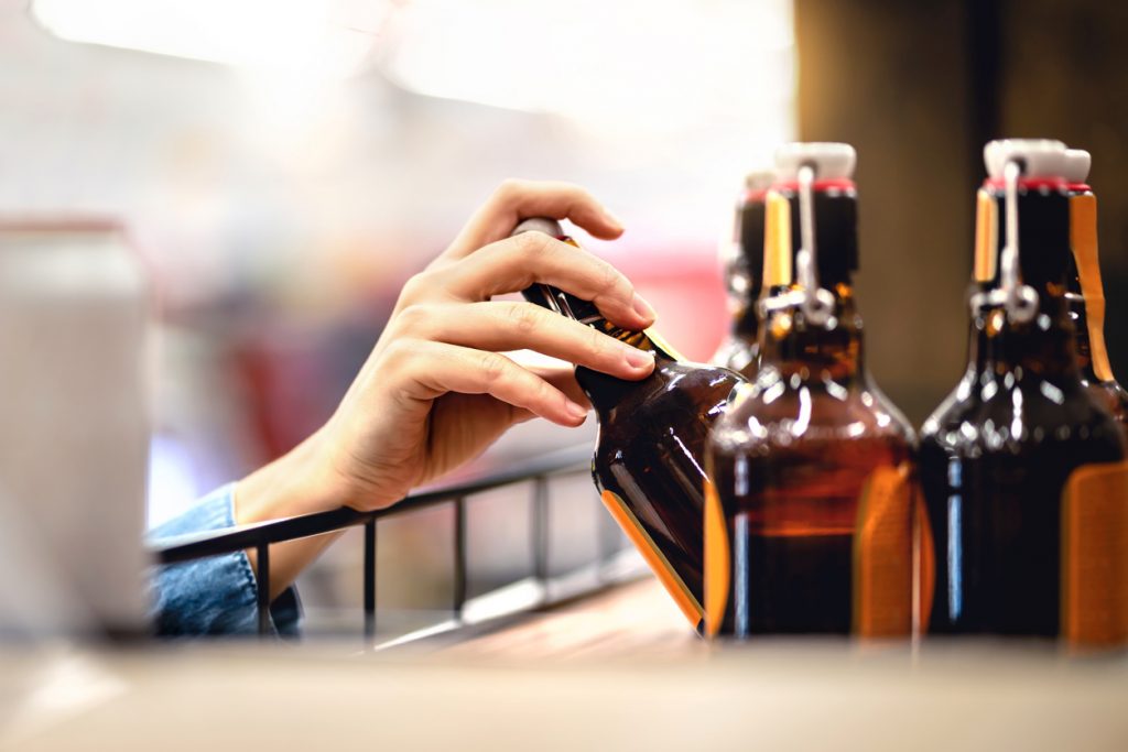hand taking a craft bottle off a shelf
