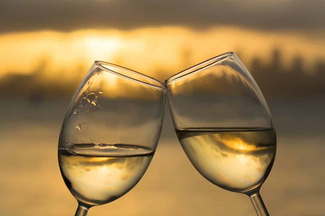Clinking white wine glasses at sunset Clinking white wine glasses at sunset