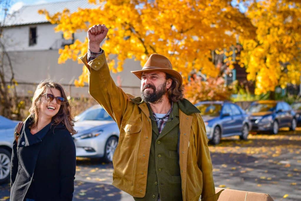 Suz and Westwind Ciders cidermaker Fabio enthusiastically talking shop while walking down a street with Fall Foliage