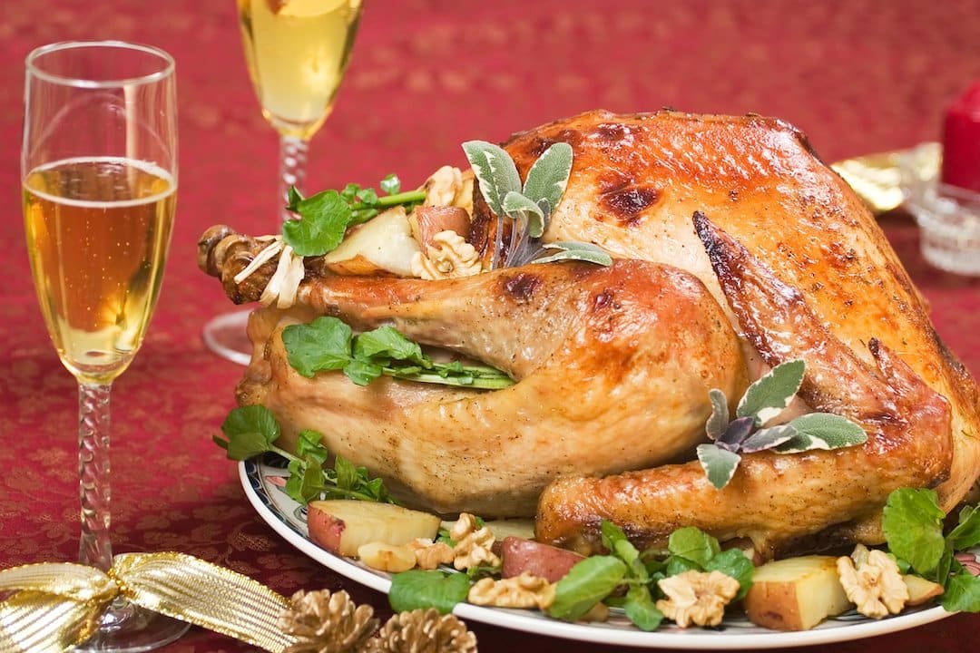 Garnished turkey on a holiday decorated table with candle and flutes of cider